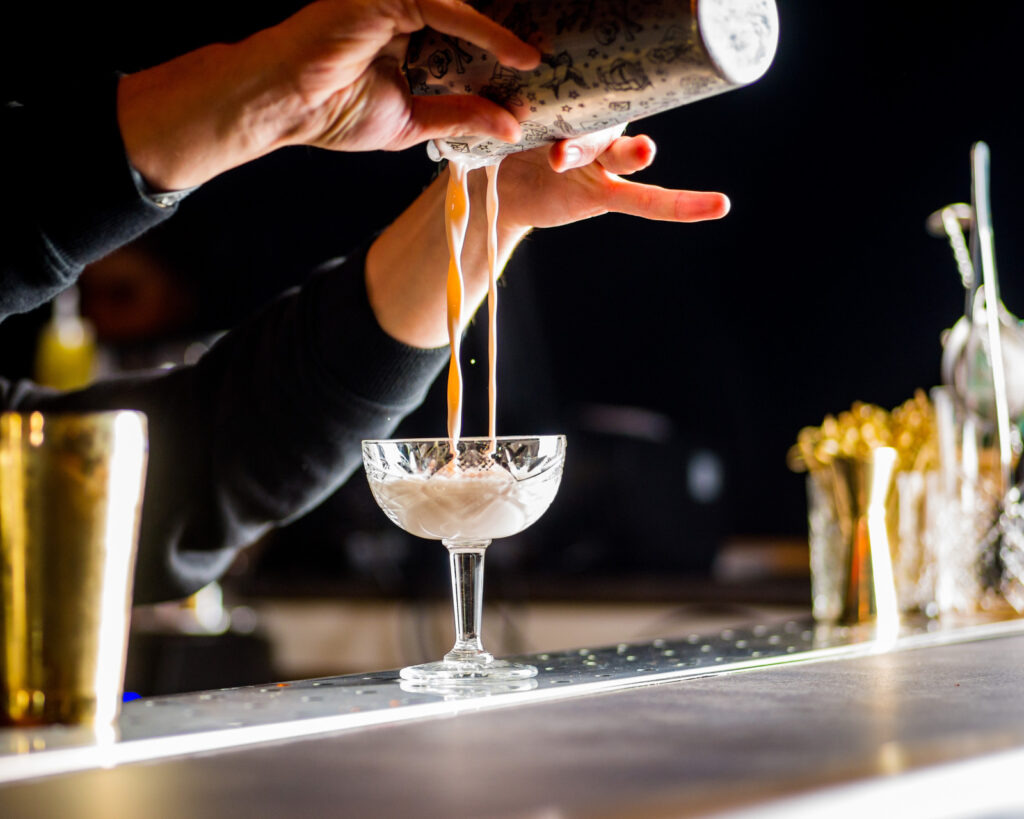 bartender is preparing a cocktail. Bartender pours a cocktail